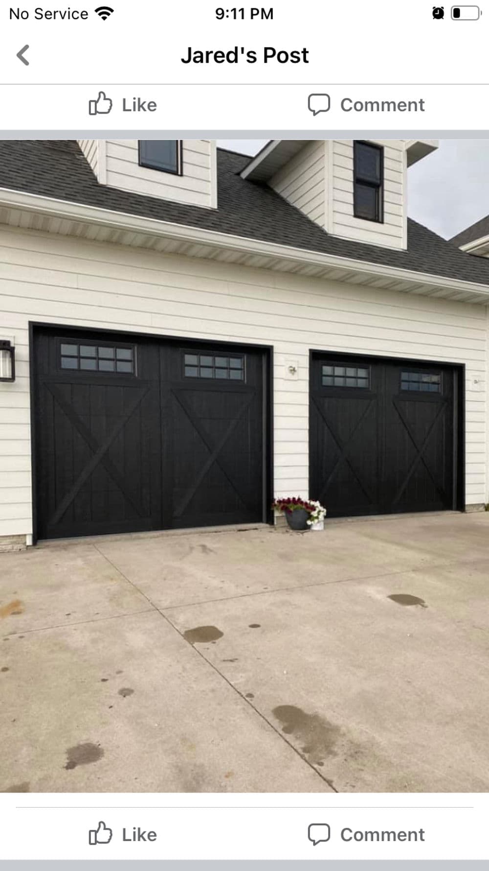 Two stylish black garage doors with window panels on a modern home exterior.