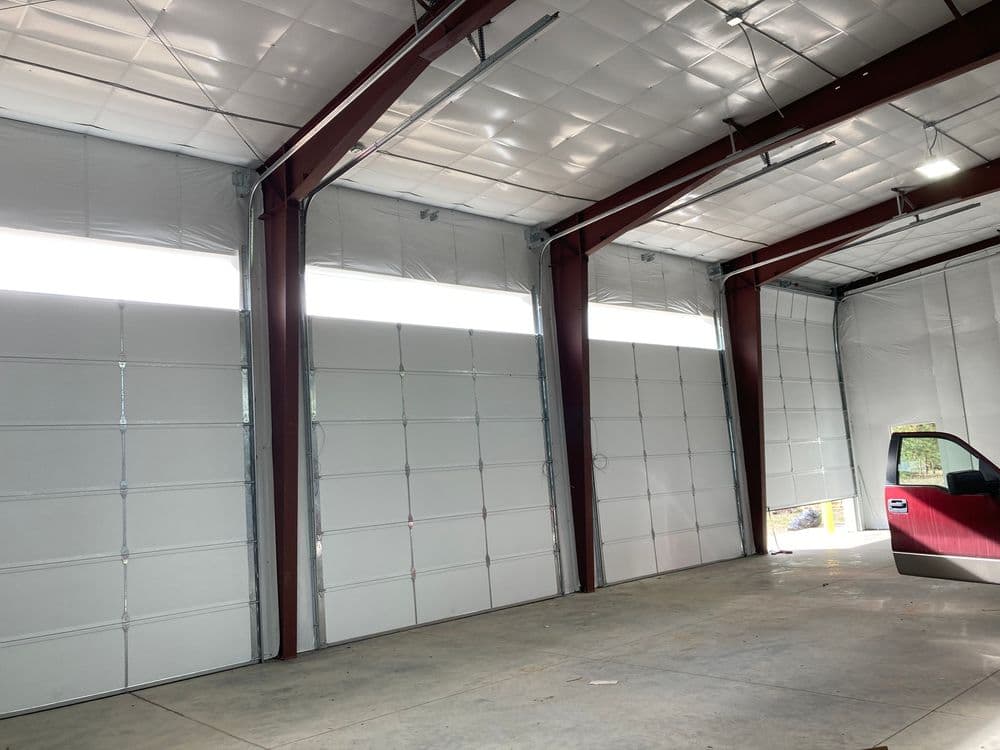 Interior of a spacious industrial garage with high ceilings and large roll-up doors.