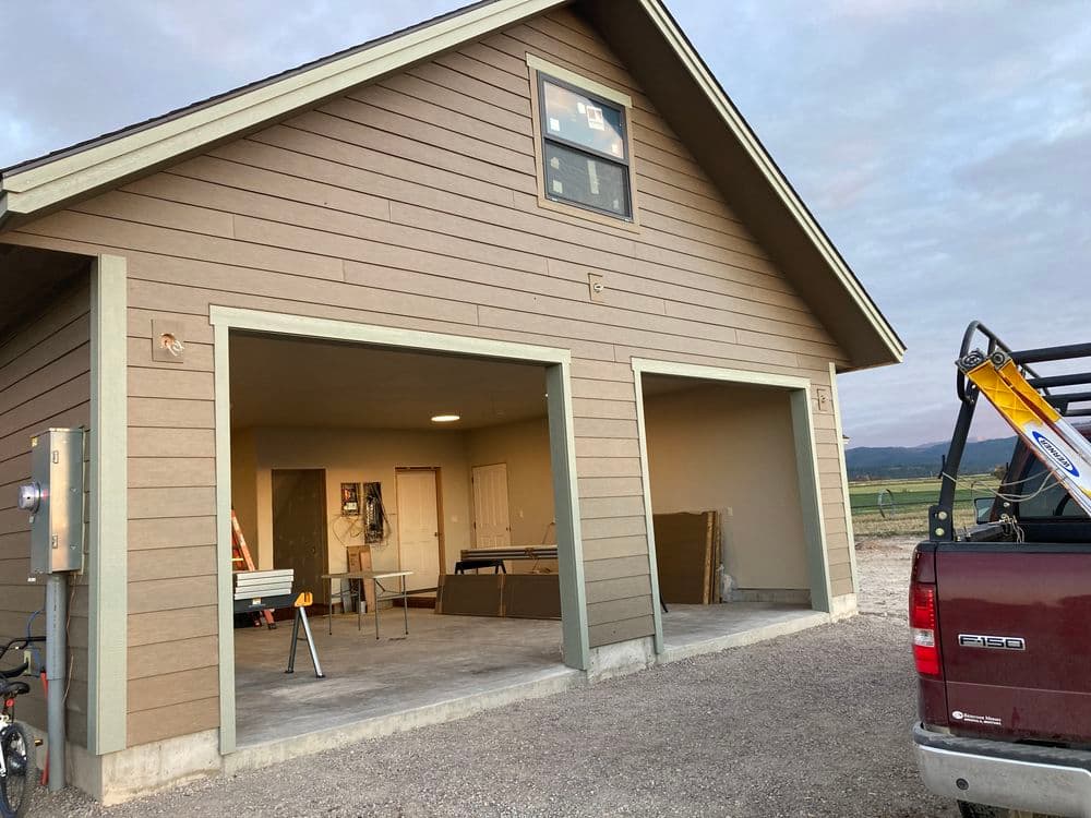 Newly constructed garage with open doors, featuring interior framing and tools visible.