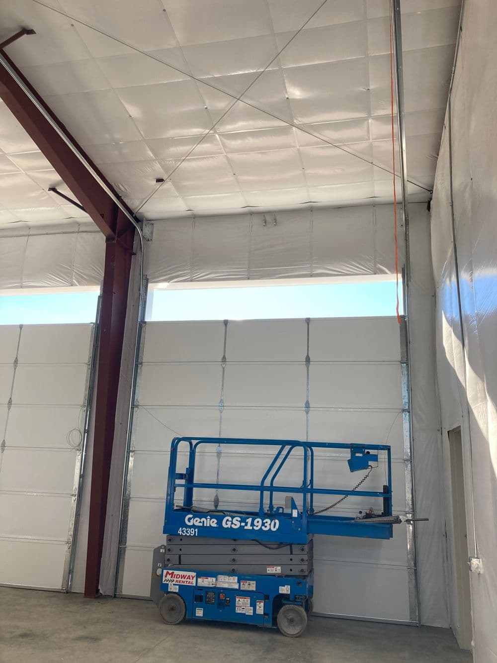 Blue Genie GS-1930 lift inside an industrial building with high ceilings and white walls.