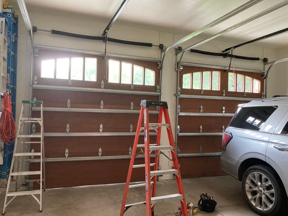 Interior of a garage with wooden doors, a car, a ladder, and tools for renovation.