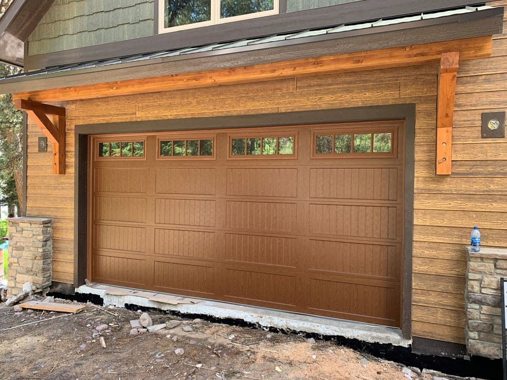 Brown wooden garage door on a rustic home with stone accents and timber framing.