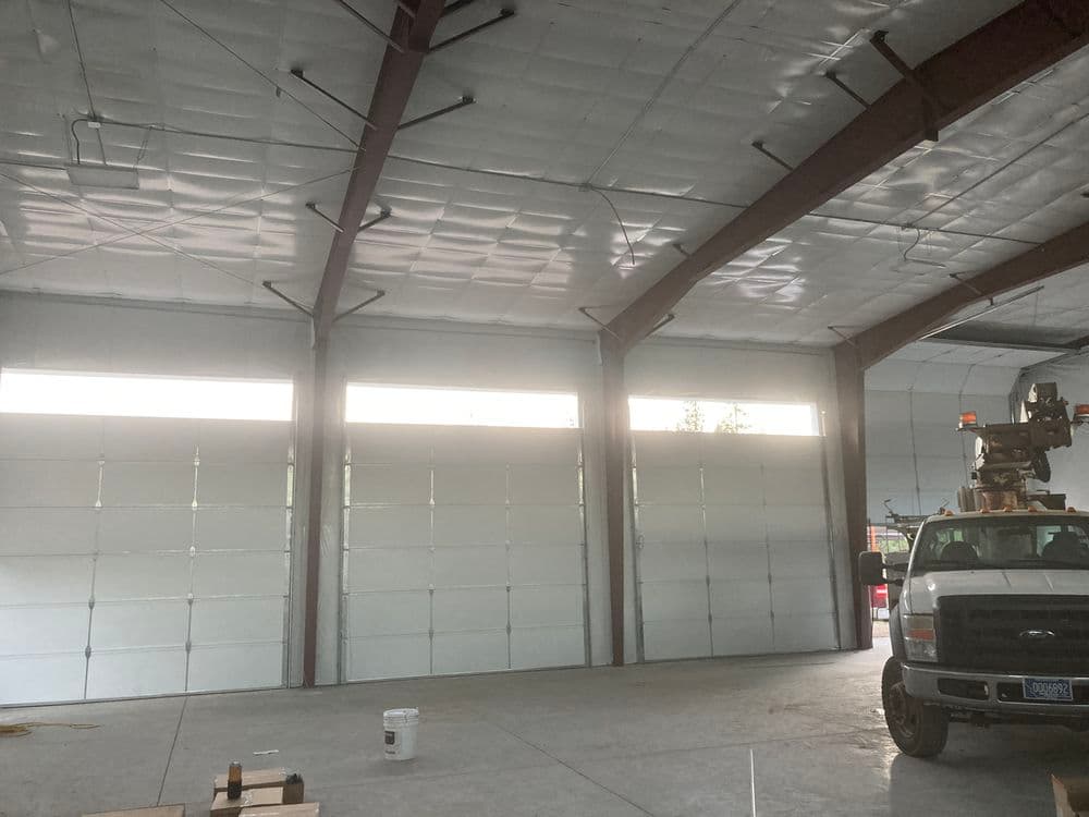 Inside view of a spacious industrial garage with three large doors and a work truck.