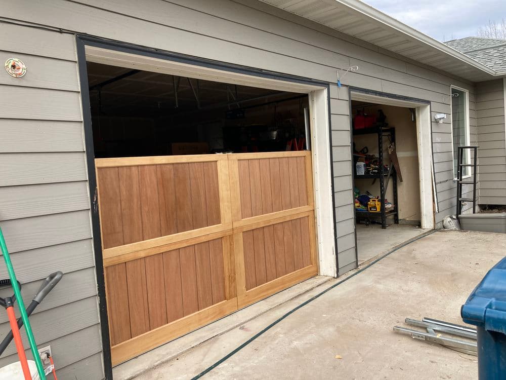 Modern garage with wooden doors open, showcasing organized tools and equipment inside.