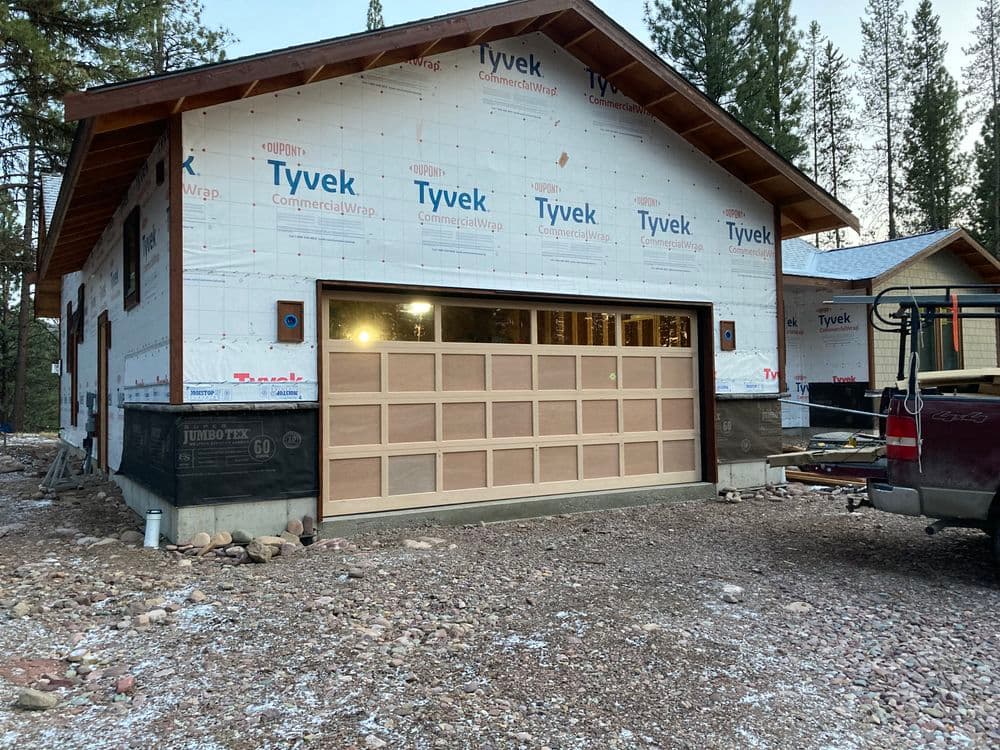 Newly constructed house with garage door, wrapped in Tyvek for insulation and protection.