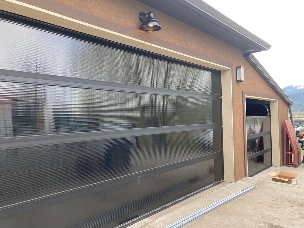 Modern garage with sleek glass doors, exterior lighting, and a well-maintained entrance.